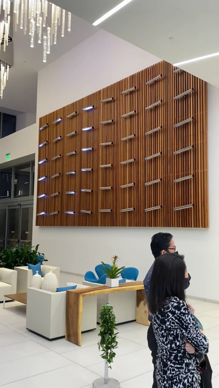 Completed bank lobby with a large lit wood-slat feature wall and lounge seating