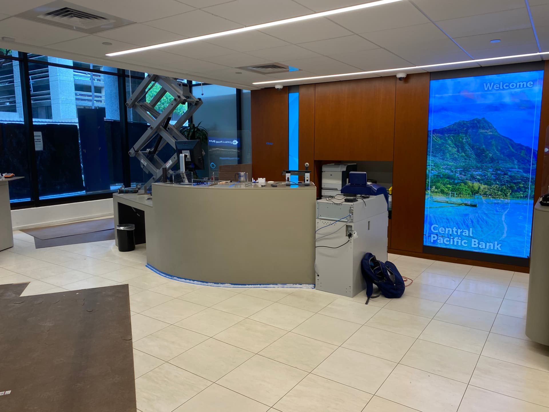 Central Pacific Bank branch lobby with curved teller pod, wood paneling, and a large digital welcome display